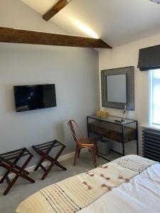 a bedroom with a bed and a tv and a chair at The Cherry Tree in Kingston Blount