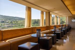 une rangée de tables et de tabourets dans un restaurant avec de grandes fenêtres dans l'établissement Hotel Fundador, à Guimarães