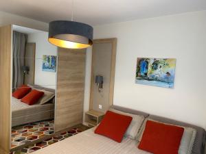 1 dormitorio con cama con almohadas rojas y espejo en Arletti Luxury Apartment en Ruse
