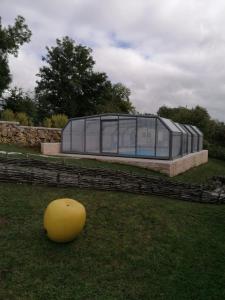 ein großes Glashaus mit gelbem Ball im Gras in der Unterkunft Gîte La feuille d'Acanthe in Bucilly