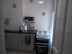 a small kitchen with a stove and a microwave at Kelso House holiday flats in Blackpool +21 photos