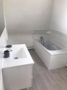 een witte badkamer met een bad en een wastafel bij Studio Lilouna avec parking privé in Le Tréport