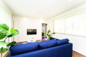 a living room with a blue couch and a tv at Shiga Lakeside Villa in Imazu