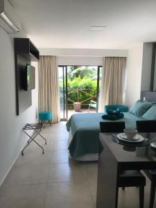 1 dormitorio con cama, mesa y TV en Flats Baia dos Porcos, en Fernando de Noronha