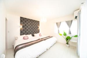 a white bedroom with a large bed with pink pillows at Shiga Lakeside Villa in Imazu