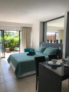 a bedroom with a bed and a table and a dining room at Flats Baia dos Porcos in Fernando de Noronha