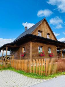 ein Holzhaus mit Blumen vor einem Zaun in der Unterkunft Liptovské Chaty in Liptovský Mikuláš