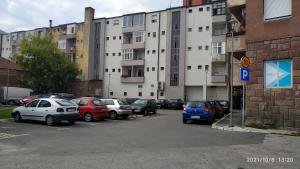 un estacionamiento con autos estacionados frente a un edificio en Apartman Rada en Pirot