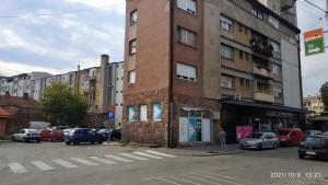 un edificio alto de ladrillo con coches estacionados en un estacionamiento en Apartman Rada en Pirot