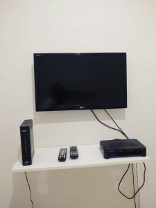 un televisor y controles a distancia en una estantería blanca en Santana Temporada - Nossa Senhora de Copacabana Apartments, en Río de Janeiro