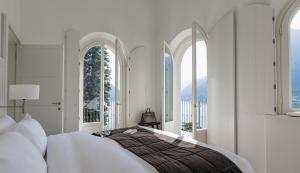 a bedroom with a large bed with windows at Villa Làrio Lake Como in Pognana Lario