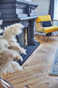 - un salon avec une cheminée et une chaise jaune dans l'établissement Demeure de Manneville - SPA - 1Km des plages de Cabourg, à Dives-sur-Mer