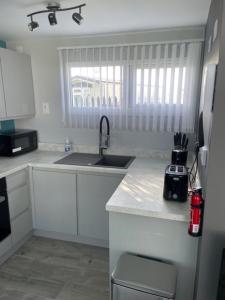 a white kitchen with a sink and a window at 52 Cherry Park Chalet in Chapel Saint Leonards
