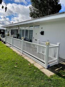 a white house with a white fence in the grass at 52 Cherry Park Chalet in Chapel Saint Leonards