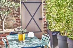 a table with a potted plant on a patio at Demeure de Manneville - SPA - 1Km des plages de Cabourg in Dives-sur-Mer