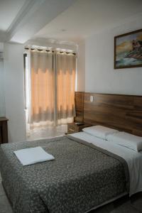 a bedroom with two beds and a large window at Hotel Masseilot in Santana do Livramento