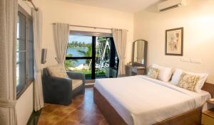 um quarto com uma cama, uma cadeira e uma janela em BluSalzz Villas - The Ambassador's Residence, Kochi - Kerala em Cochin