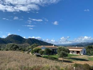 a house on a hill with mountains in the background at Macciuneddu Country Retreat in Golfo Aranci