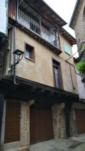 Edificio antiguo con 2 puertas y balcón en Casa Fuente la Calle, en San Martín del Castañar