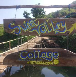 a wooden sign with graffiti on a bridge at Sweet Valley Cottages in Arambol