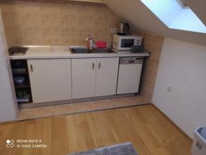 eine kleine Küche mit einer Spüle und einer Mikrowelle in der Unterkunft Apartman Kupres Centar in Kupres