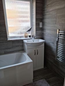a bathroom with a tub and a sink and a window at Waterfront Retreat - Modern Apartment in Burnham on Crouch