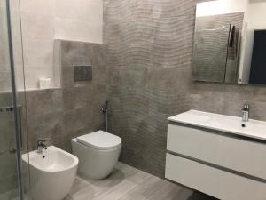 bagno con servizi igienici, lavandino e specchio di RoomsCarli a Comacchio