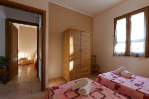 a bedroom with two beds and a cabinet and windows at Tenuta Li Fani Residence Hotel in Marina di Pescoluse