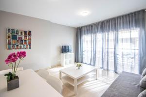 sala de estar con sofá blanco y mesa en Recogidas Apartment by A3Rentals, en Granada