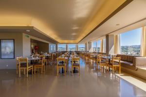 uma sala de jantar com mesas, cadeiras e janelas em Hotel Fundador em Guimarães