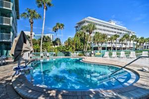 a swimming pool at a resort with palm trees at Coastal Clearwater Condo Half Mile to Beach! in Clearwater Beach