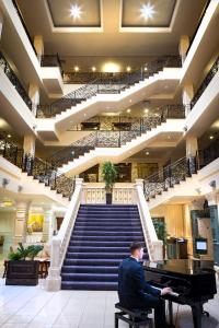 Ein Mann, der an einem Klavier in einem Gebäude mit Treppen sitzt. in der Unterkunft The Heritage in Killenard