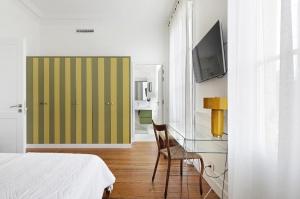 a bedroom with a bed and a chair and a television at Le Clou de Louis in Bordeaux