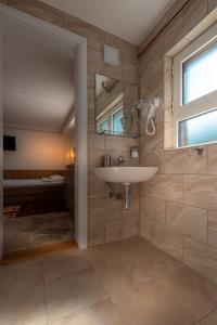ein Bad mit einem Waschbecken und einer Dusche mit einem Fenster in der Unterkunft Kuća Jankovića in Vrnjačka Banja