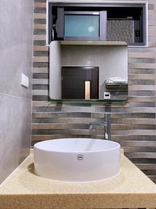 baño con lavabo blanco y TV en Saint Malo Homestay en Lugu