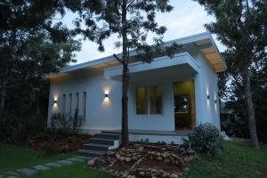 a white house with a tree in front of it at Blue Valley Estate - Mountain View Villa in Yercaud