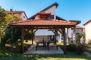 a wooden gazebo with a table in the yard at Kuća Jankovića in Vrnjačka Banja