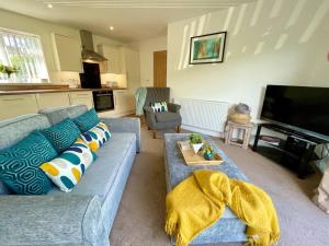 a living room with a blue couch and a television at Stylish Boutique Bungalow in Felixstowe
