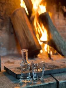 a bottle and a glass sitting next to a fire at AETIA-TSIOURGIAKA in Aetia