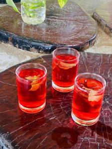 three glasses of juice on a wooden table at Bat Rice Resort in Battambang