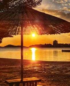 an umbrella sitting on the beach with the sunset at Vodice Mladen apartman za familiju in Vodice