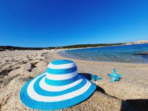 ein blauer und weißer Hut am Strand in der Unterkunft Le Villette di Ruoni in Santa Teresa Gallura