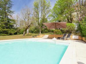 ein großer Pool mit Sonnenschirm und Stühlen in der Unterkunft Manoir La Peyrade in Brouchaud