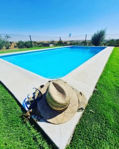 a straw hat sitting next to a swimming pool at FINCA VALDELAJARA a 20 minutos de Puy du Fou in Toledo