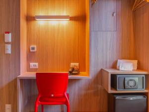 uma cadeira vermelha num quarto com um micro-ondas em Hotel Moov Porto Alegre em Porto Alegre
