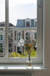 a vase filled with flowers sitting on a window sill at Huize Copes apartment Den Haag, 2 bed, 2 bath in The Hague +14 photos