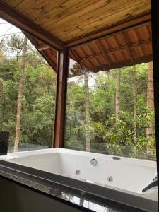 a bath tub in a room with a window at MD Luar da Montanha in Monte Verde