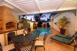 a patio with a table and chairs and a swimming pool at Anchorage Guesthouse in Port Elizabeth
