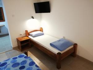 um pequeno quarto com uma cama e uma televisão na parede em Sobe i apartmani Simic em Ribarska Banja