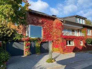 a building covered in red ivy at "An der alten Mühle 1" Große Fewo 110 qm, sehr zentral gelegen, zwei Schlafzimmer, Südbalkon, Gartenterrasse & Wallbox in Bad Bentheim